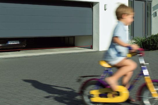 Poika pyöräilee autotallin edessä